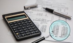 financial documents with calculator, magnifying glass and pen with cap removed