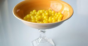 candy dish with round yellow candy pieces inside.