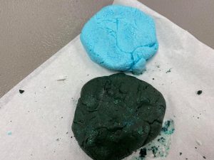 closeup of homemade modeling compound in light blue and dark green with glitter