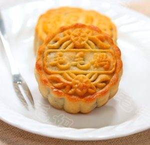 closeup of two moon cakes on a white plate with a fork