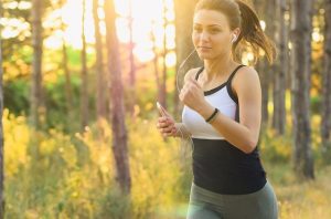 closeup of young Caucasian woman jogging outdoors and wearing white earbuds