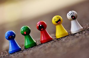 five multicolored game pieces with facial expressions