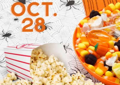 spilled box of popcorn next to bowl of Halloween candy. Spider pattern background.
