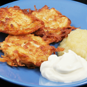 closeup of plate of latkes with sour cream